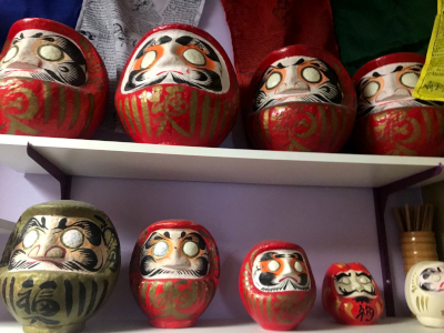 photo credit: madi, photograph of a shelf full of daruma figures, eyes unpainted